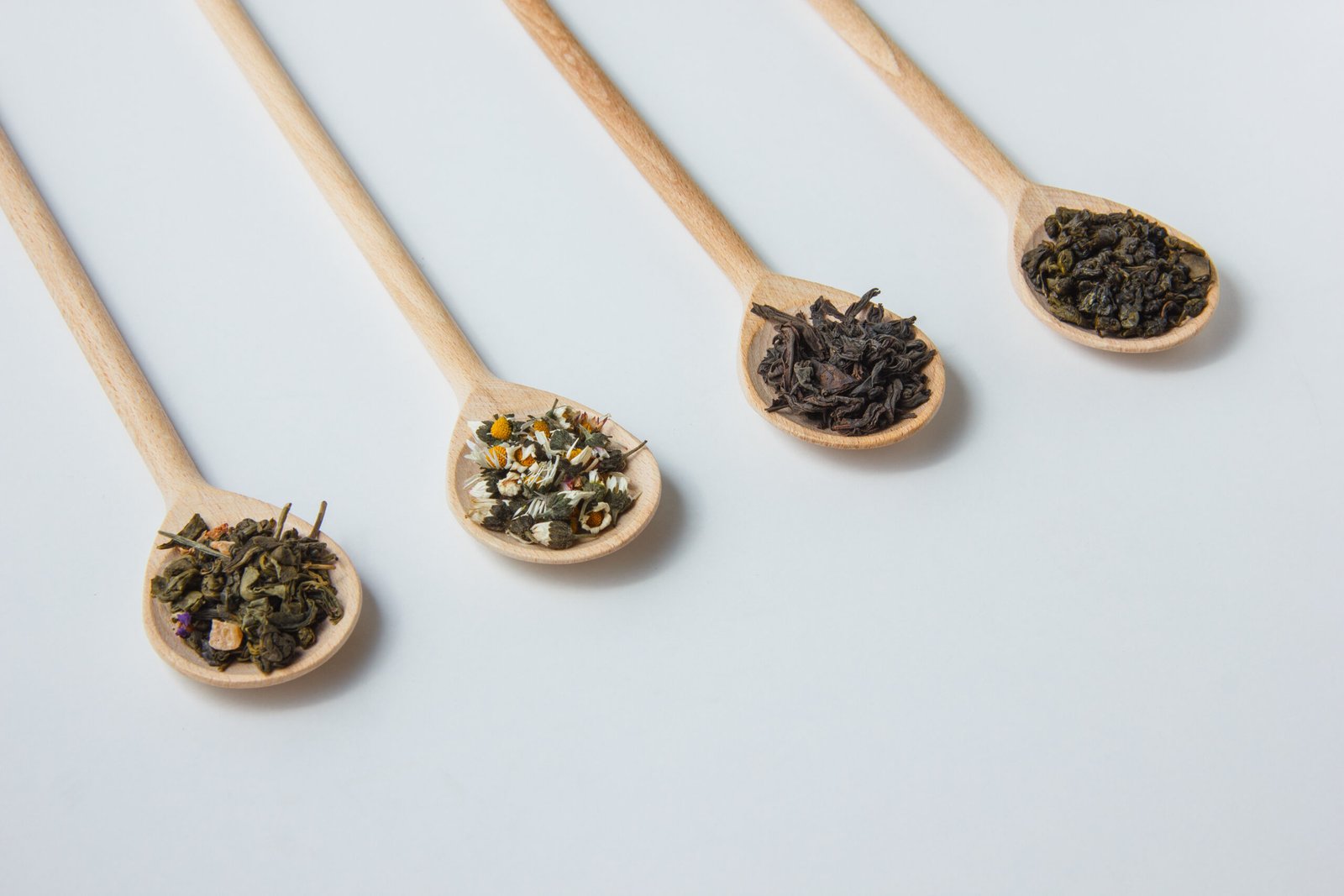 high angle view dry chamomile in spoon with tea herbs on white background. horizontal